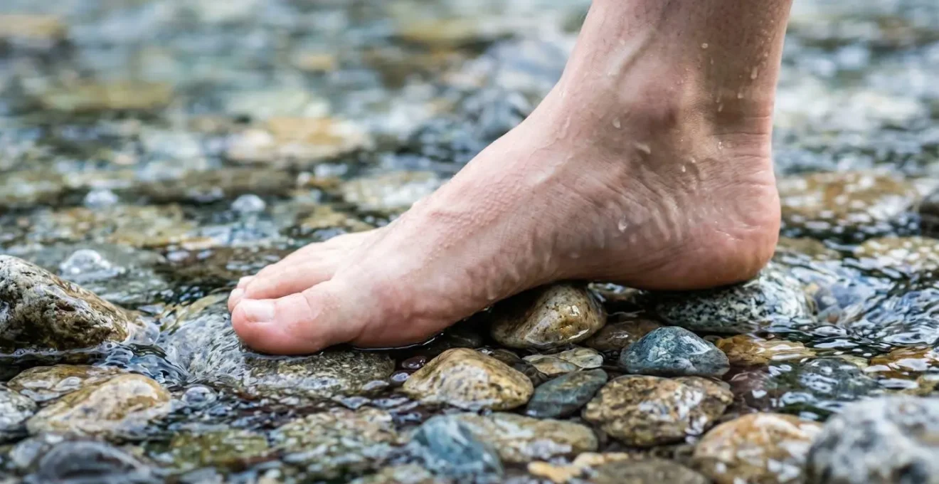 Piedi che camminano su sassi di fiume in acqua fredda